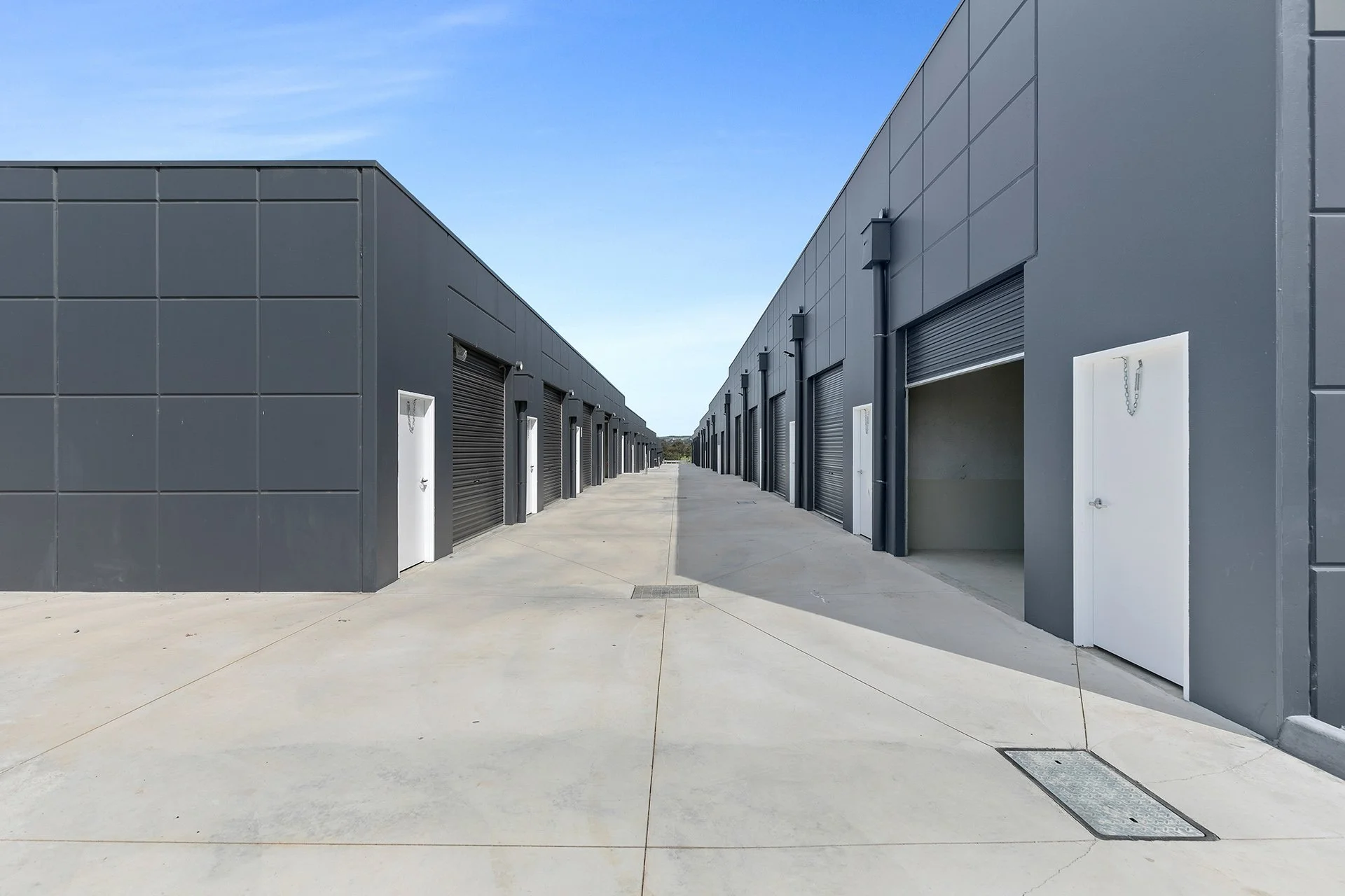 Concrete driveway between two rows of storage units with roller doors at AlterSpaces Breakwater
